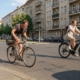 Radfahrer schwitzt beim Treten, während ein E-Bike-Fahrer entspannt an derselben Kreuzung vorbeifährt
